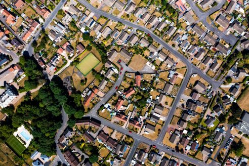 An aerial view directly above a suburban community on the outskirts of a city with intertwining roads and neighbourhoods